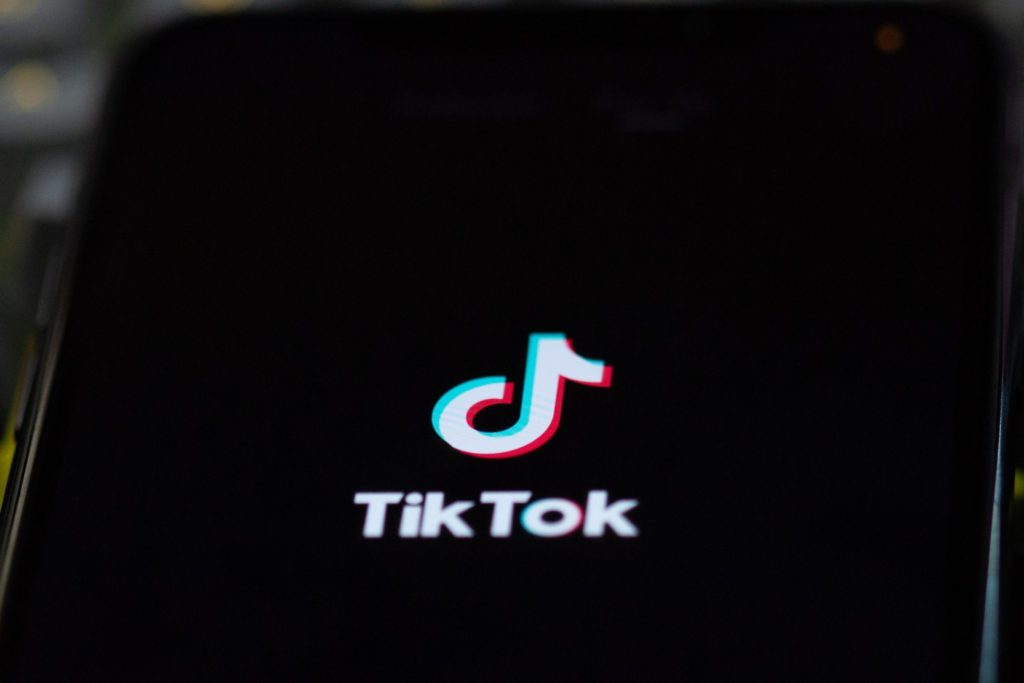 Black phone screen with 'Tik Tok' on the screen in white letters and the 'Tik Tok' logo