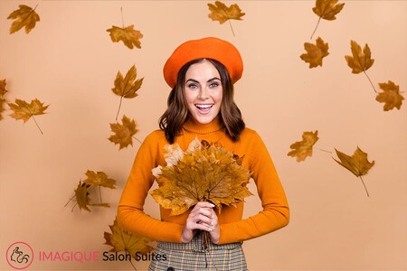 Lady holding a brown leaf dressed in fall colors and fall hair accessories.